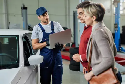 Mechaniker erklärt einem älteren Paar den Zustand ihres Autos