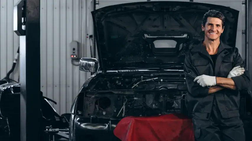 Automechaniker steht vor einem Auto mit geöffneter Motorhaube