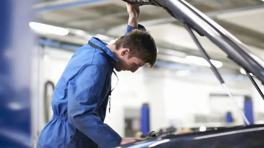 Mechaniker überprüft den Motorraum eines Fahrzeugs in der Werkstatt