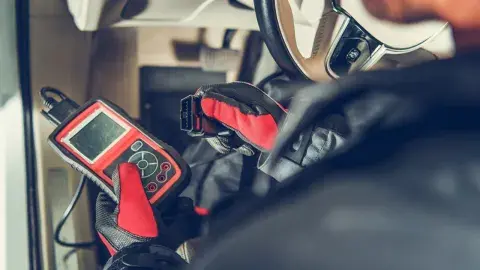 Mechaniker verwendet OBD2-Diagnosegerät im Innenraum eines Autos