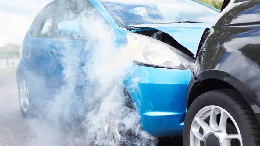 Autounfall mit stark beschädigtem blauen Fahrzeug und Rauchentwicklung